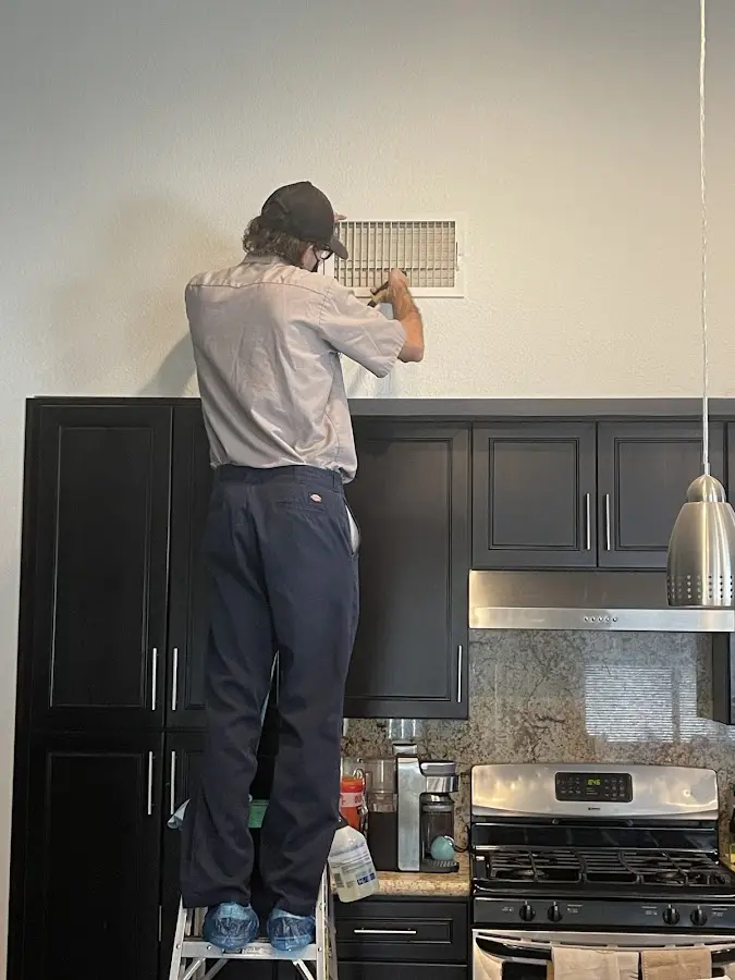 Technician inspecting an air vent during HVAC service in Okeechobee